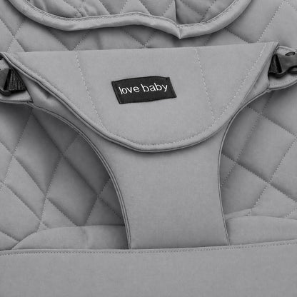 Close-up of a light gray quilted baby bouncer or seat pad with a black fabric label reading 'love baby' in white text.