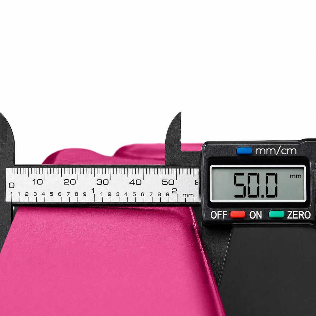 Pink tri-folding exercise mat being measured with a digital caliper to show its 50.0mm extra thick high-density foam cushioning.