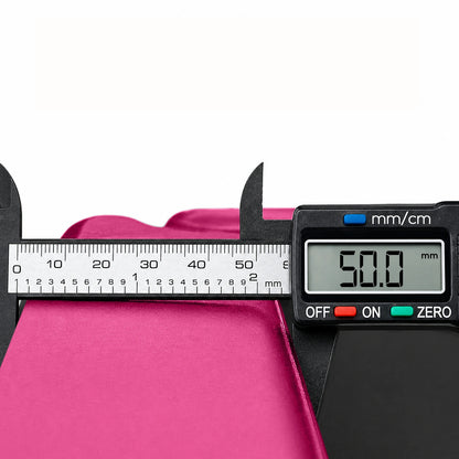 Pink tri-folding exercise mat being measured with a digital caliper to show its 50.0mm extra thick high-density foam cushioning.